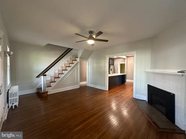 a view of an empty room with wooden floor a fireplace with a kitchen