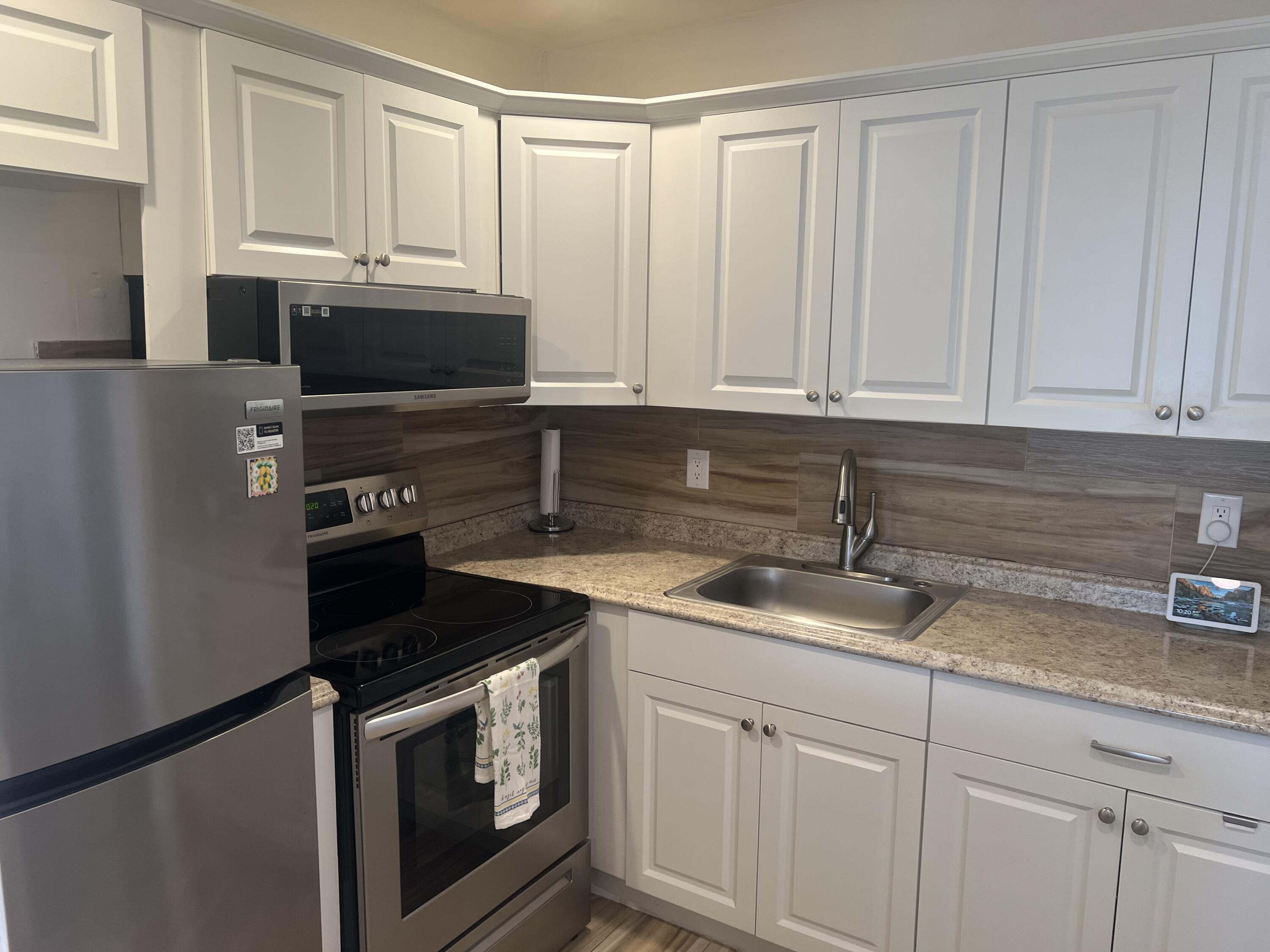 79 Dorset B Boca Raton, FL 33434 - Photo 4 of 12 a kitchen with granite countertop white cabinets and stainless steel appliances