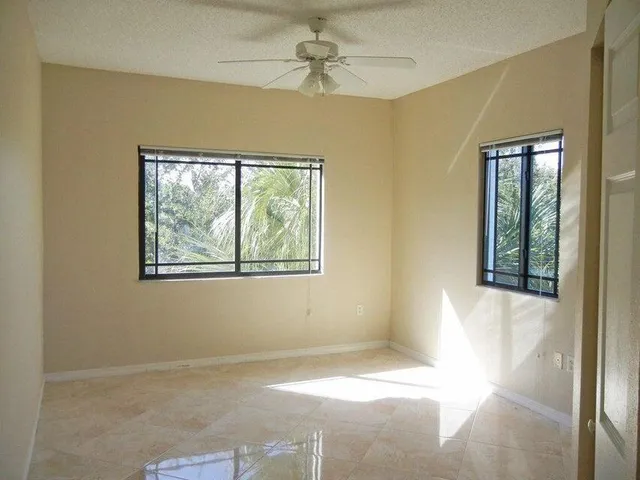 an empty room with windows and fan