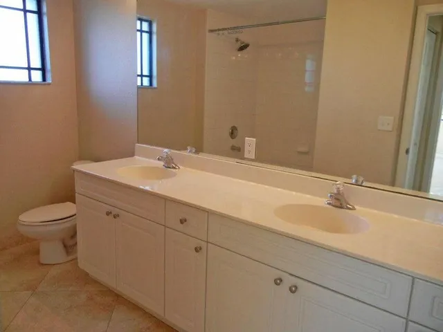 a bathroom with a granite countertop sink a toilet and a mirror