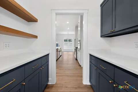 an empty room with wooden floor cabinet and windows