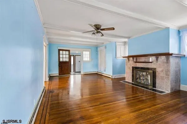 a view of an empty room with wooden floor fireplace and a window