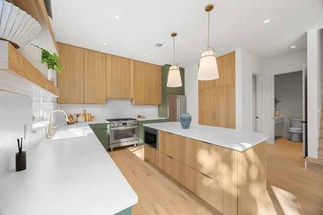 a large kitchen with kitchen island a large counter top a sink a stove and a refrigerator