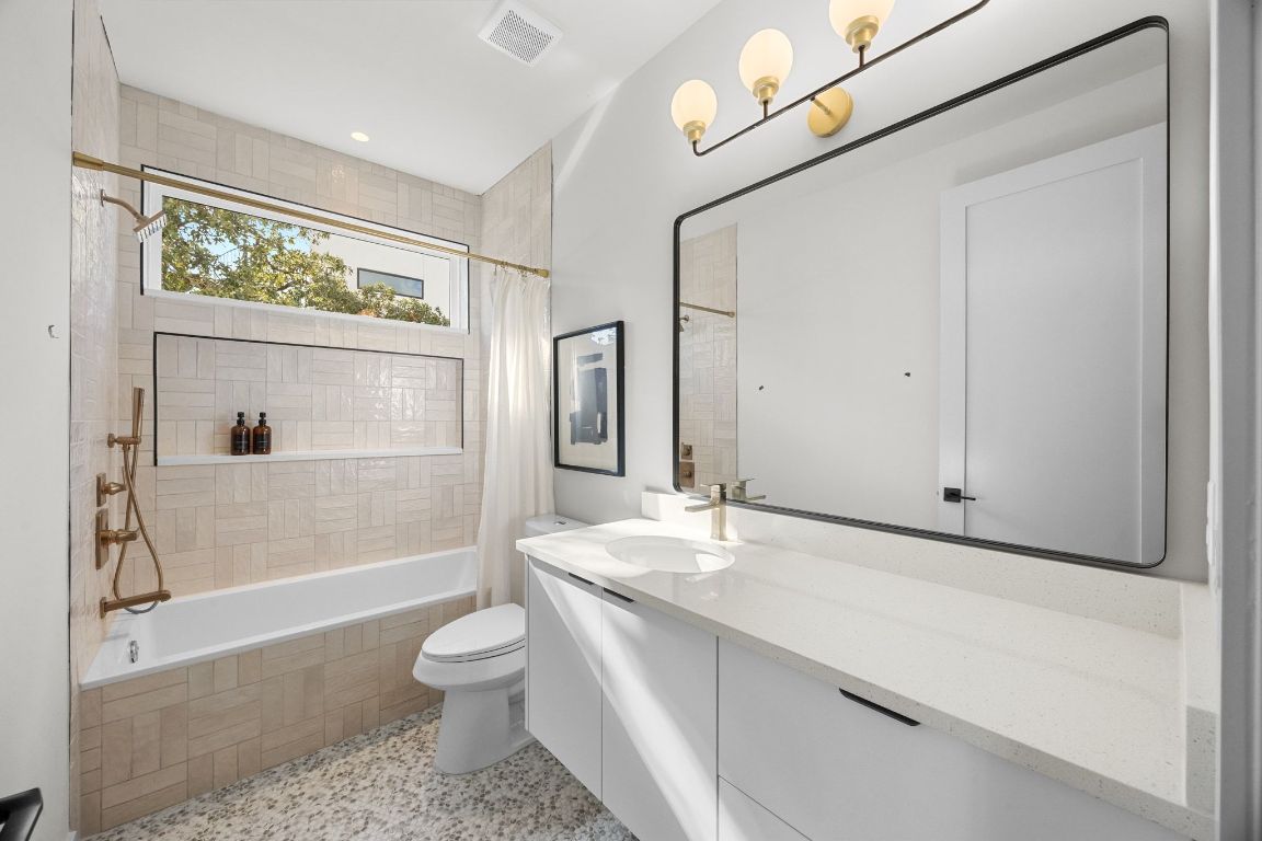 1175 Navasota Street, Unit 2 Austin, TX 78702 - Photo 29 of 40 a bathroom with a granite countertop sink toilet a large mirror a vanity and shower