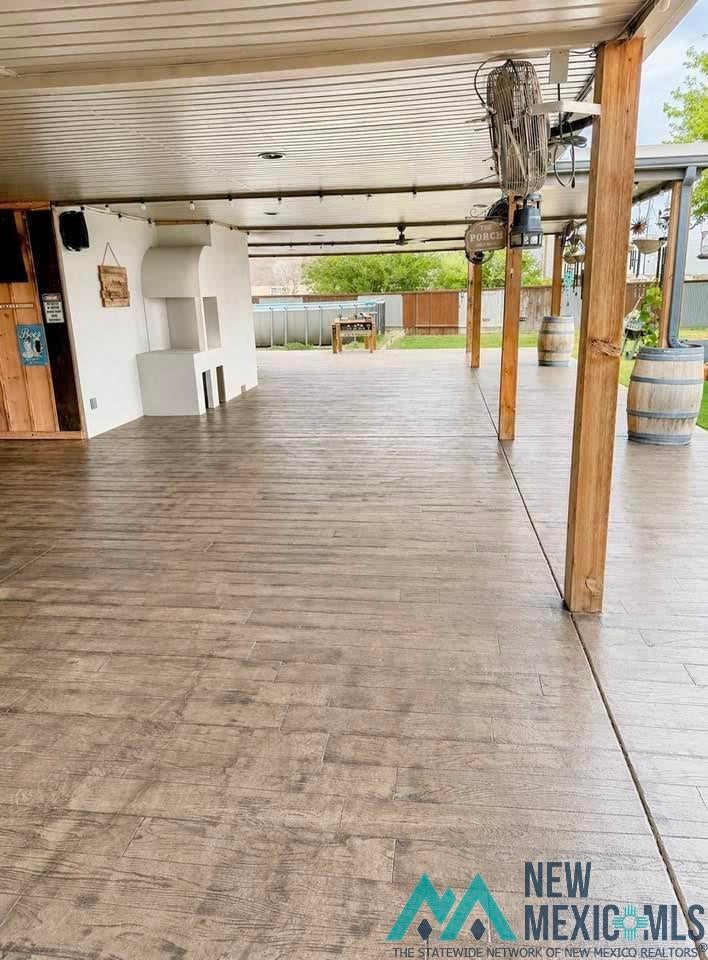 5404 Sioux Road Carlsbad, NM 88220 - Photo 68 of 100 Expansive covered patio featuring wood-finish stamped concrete flooring, a built-in outdoor fireplace, and multiple ceiling fans