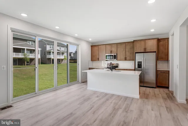 a view of kitchen with kitchen island wooden floors stainless steel appliances and sink