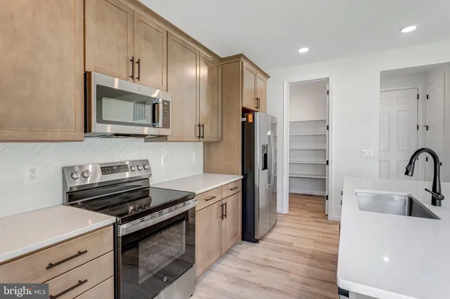 a kitchen with stainless steel appliances a stove a sink and a refrigerator