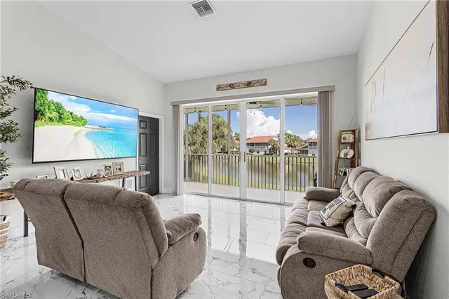 a living room with furniture a flat screen tv and a floor to ceiling window