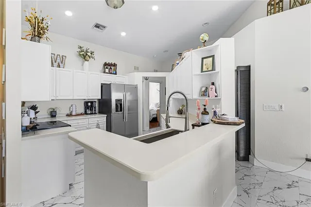 a kitchen with stainless steel appliances a sink a stove a refrigerator cabinets and living room view