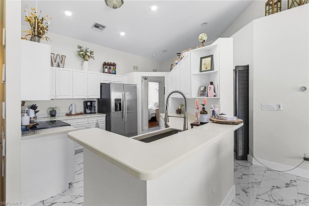 25110 Peacock Lane, Unit 201 Naples, FL 34114 - Photo 6 of 24 a kitchen with stainless steel appliances a sink a stove a refrigerator cabinets and living room view