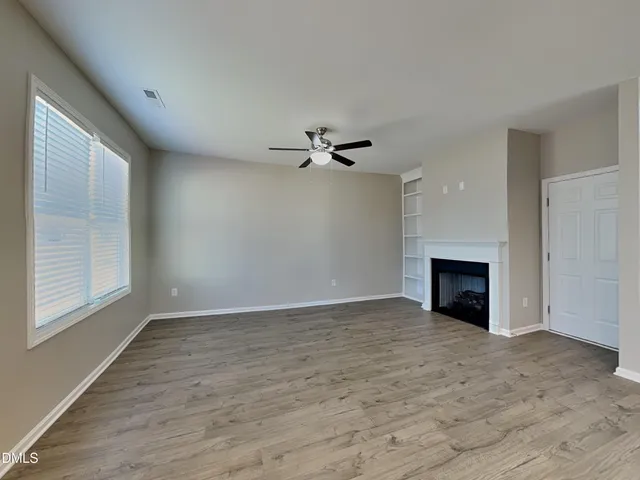 a view of an empty room with a fireplace and a window