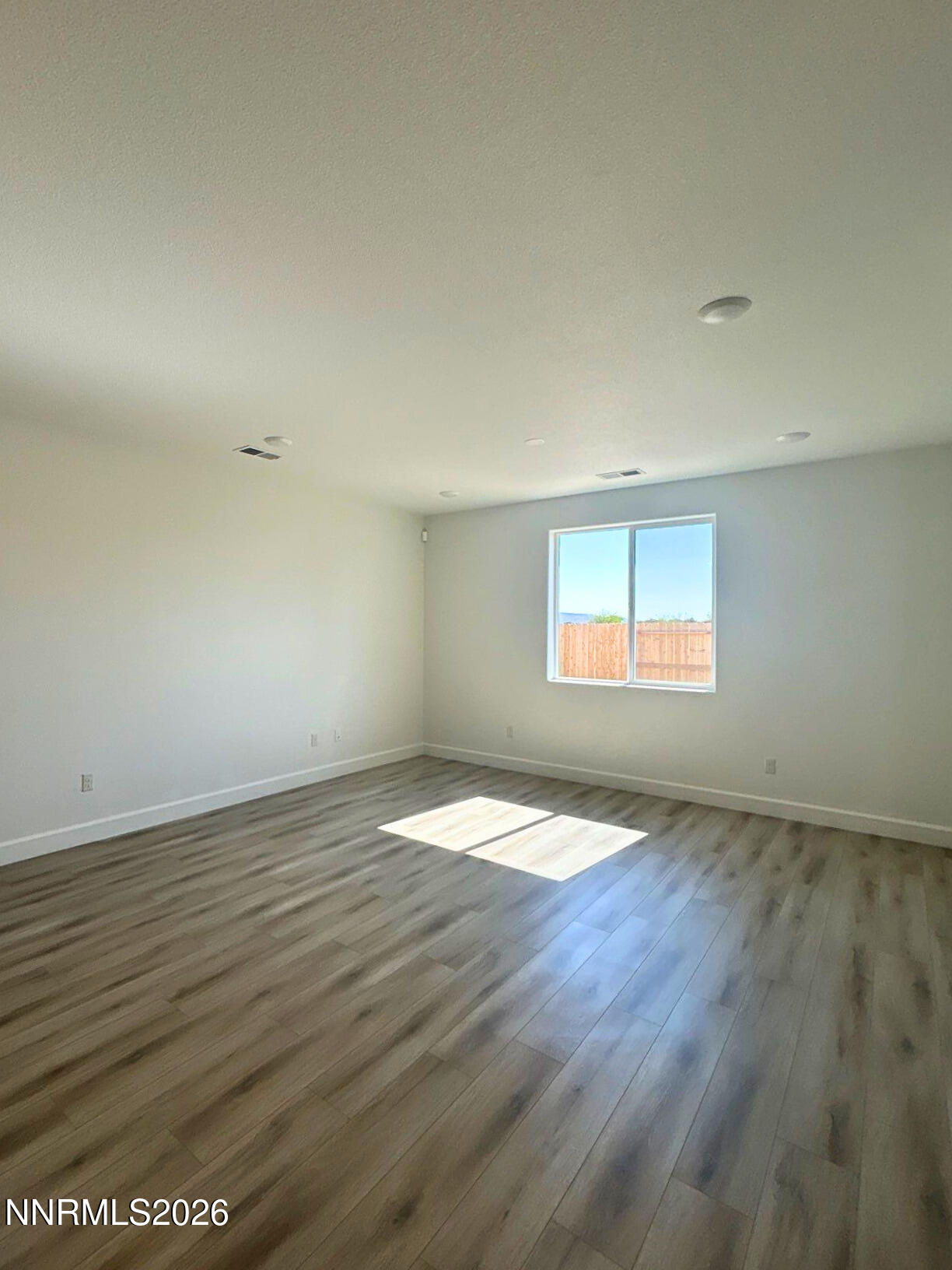 3453 Payton Way Fernley, NV 89408 - Photo 5 of 15 an empty room with wooden floor and windows