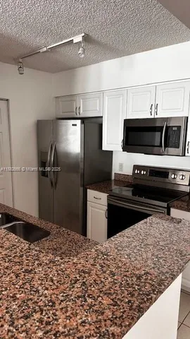 a kitchen with granite countertop white cabinets and sink