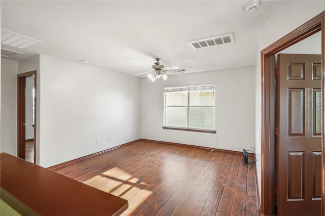 an empty room with wooden floor cabinet and windows
