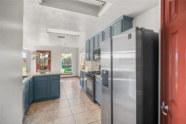 a kitchen with granite countertop a refrigerator and a stove top oven