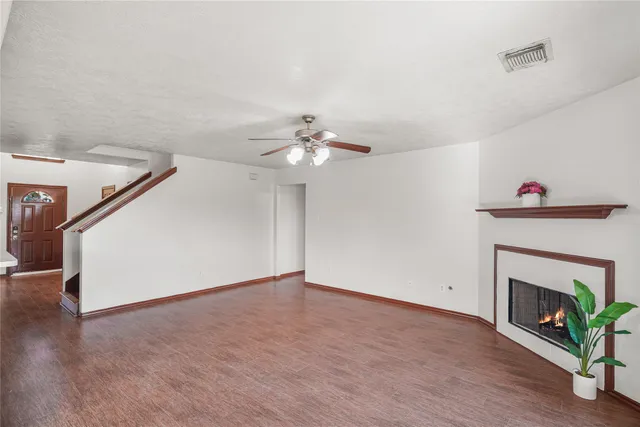 a view of an empty room with wooden floor and a fireplace