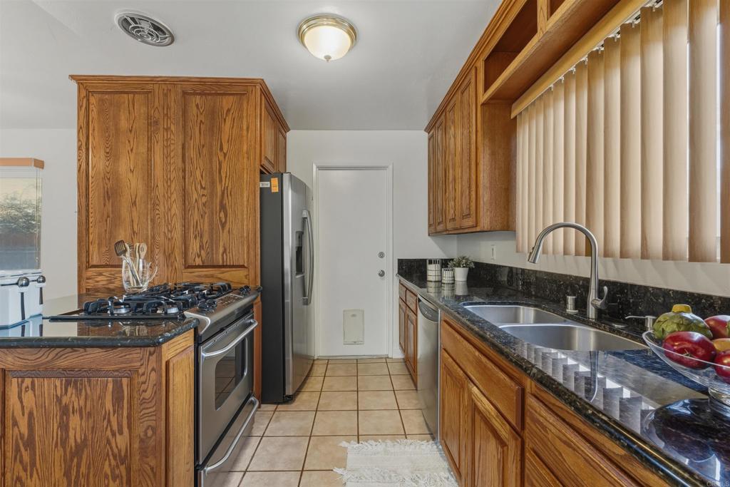 9909 Halberns Boulevard Santee, CA 92071 - Photo 11 of 35 a kitchen with granite countertop a sink stove and cabinets
