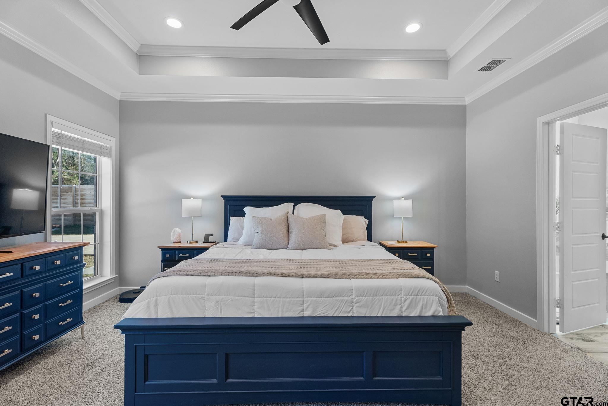 14543 Fallow Lane Tyler, TX 75706 - Photo 13 of 32 a bedroom with a bed and a flat tv screen on a dresser