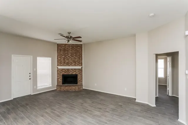 an empty room with wooden floor fireplace and windows