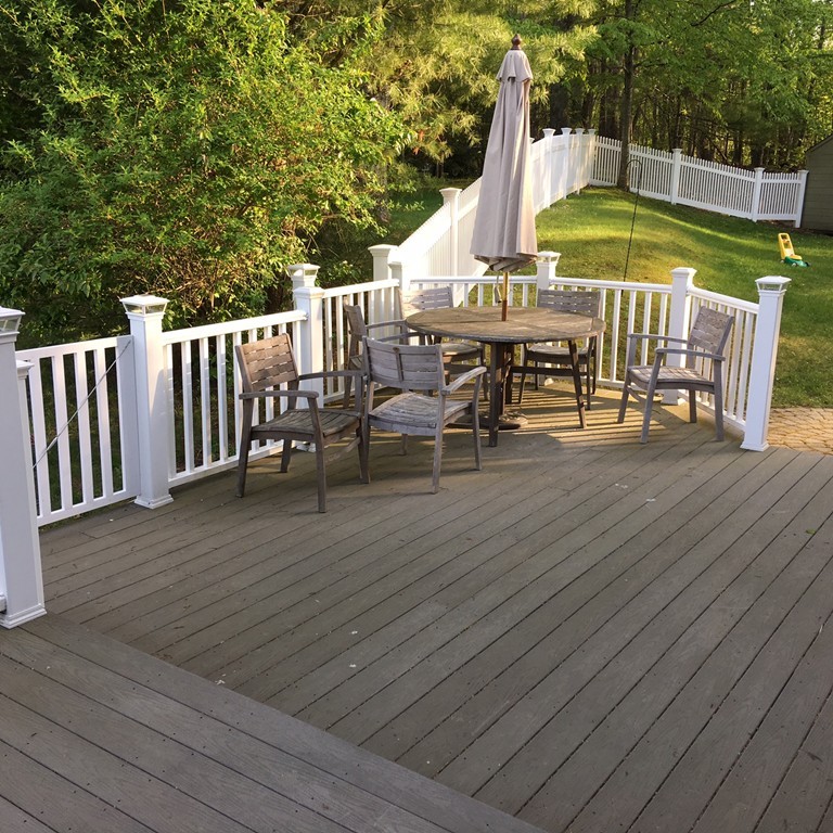 7 Middle Road Amesbury, MA 01913 - Photo 22 of 25 a view of a patio with table and chairs under an umbrella with wooden floor and fence