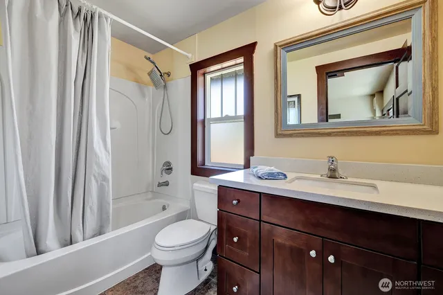 a bathroom with a granite countertop toilet a sink a mirror a and a window