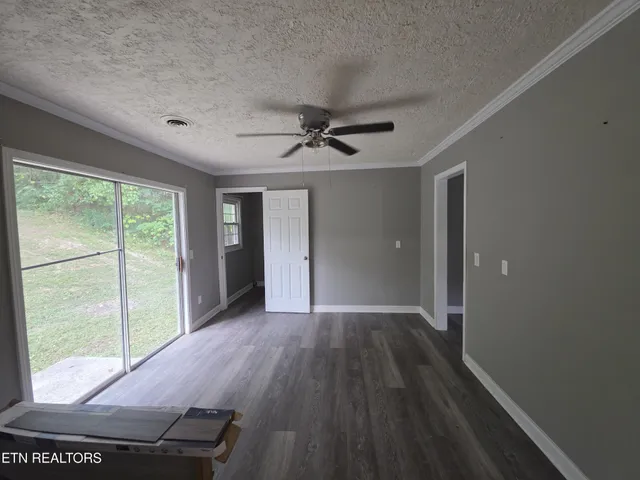 an empty room with windows and ceiling fan