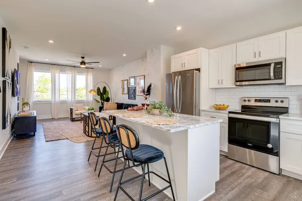 a kitchen with stainless steel appliances a stove a sink a refrigerator cabinets and a dining table with wooden floor