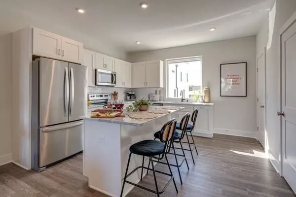 a kitchen with stainless steel appliances a refrigerator a stove a sink dishwasher and a refrigerator with wooden floor