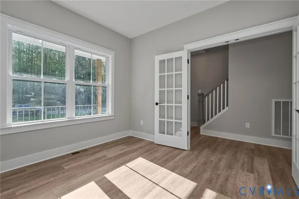 a view of an empty room with wooden floor and a window