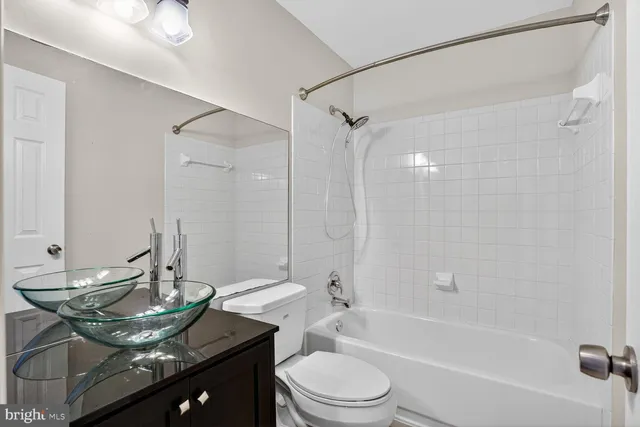 a bathroom with a granite countertop sink a toilet and shower