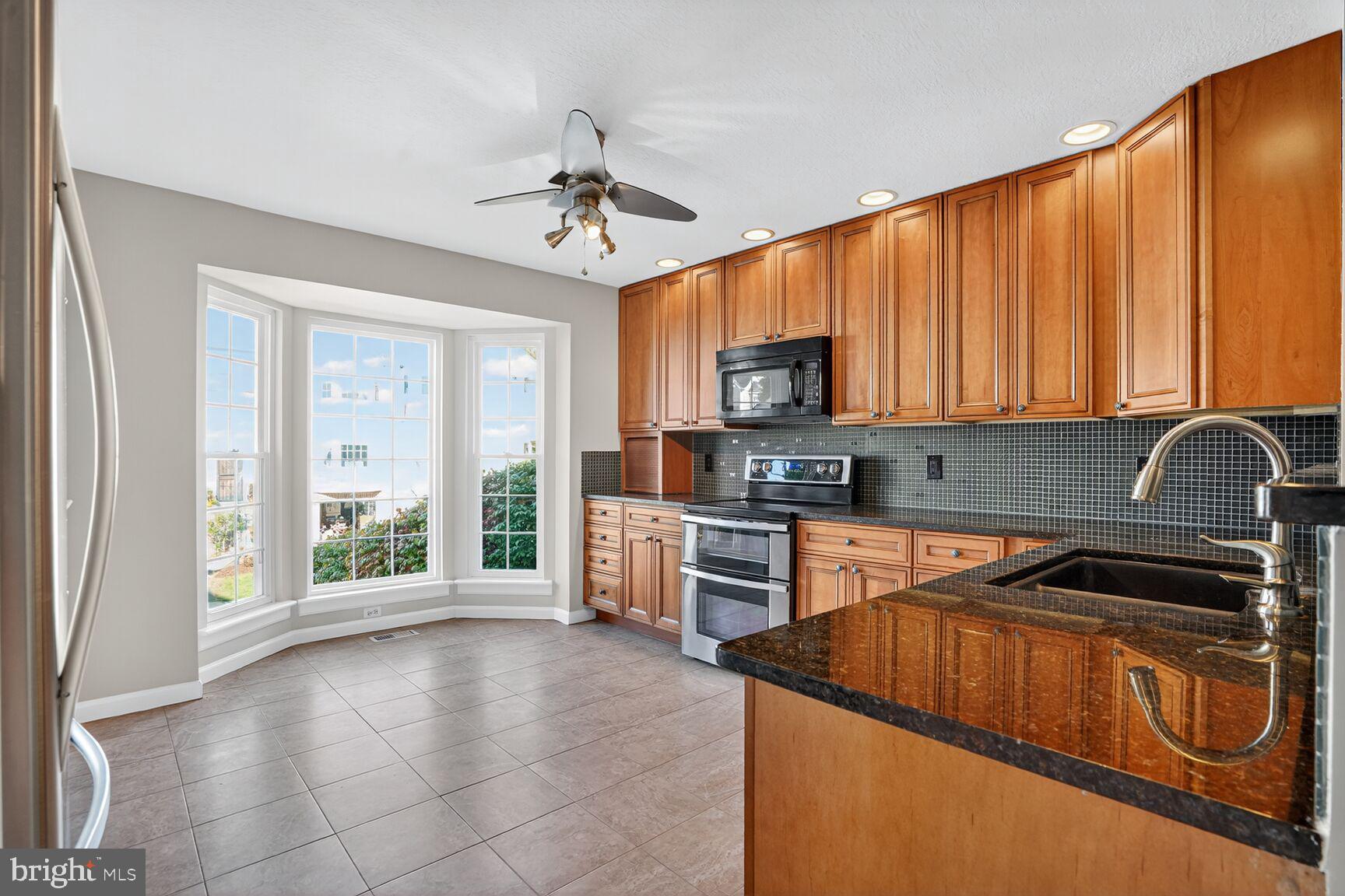 6836 Kerrywood Circle Centreville, VA 20121 - Photo 5 of 22 a kitchen with kitchen island granite countertop a stove top oven a sink a counter space and cabinets