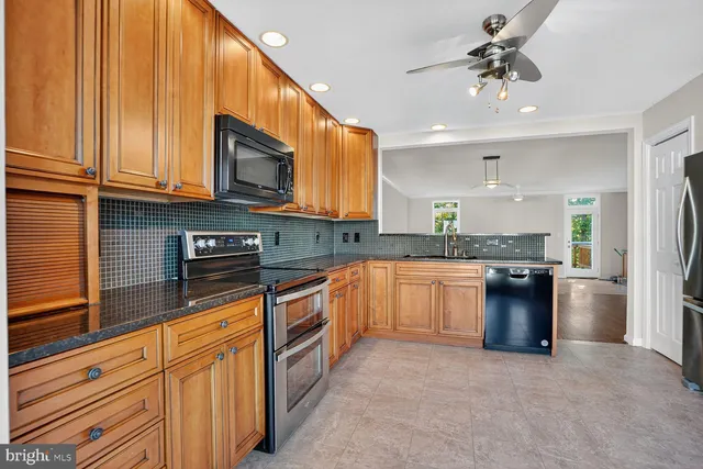 a kitchen with stainless steel appliances granite countertop a refrigerator a stove top oven a sink and dishwasher