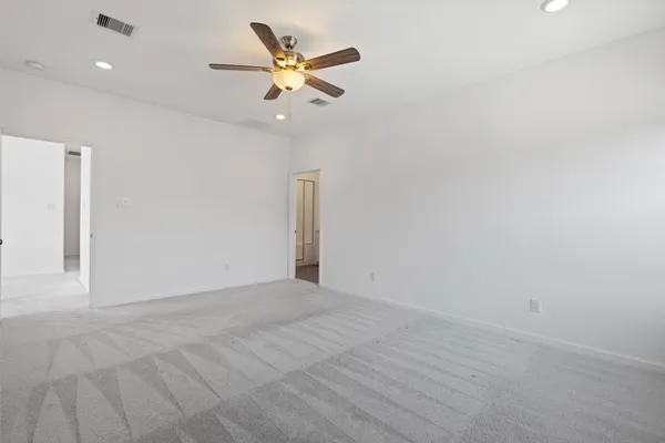 an empty room with a chandelier fan and wooden floor