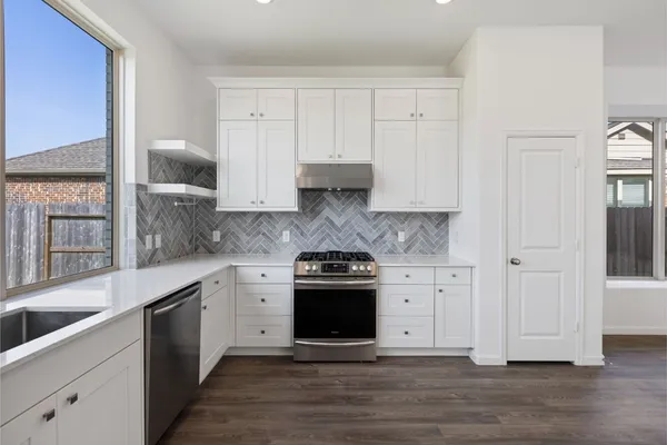 a kitchen with stainless steel appliances granite countertop white cabinets and a stove