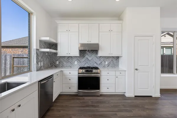 a kitchen with stainless steel appliances granite countertop white cabinets and a stove