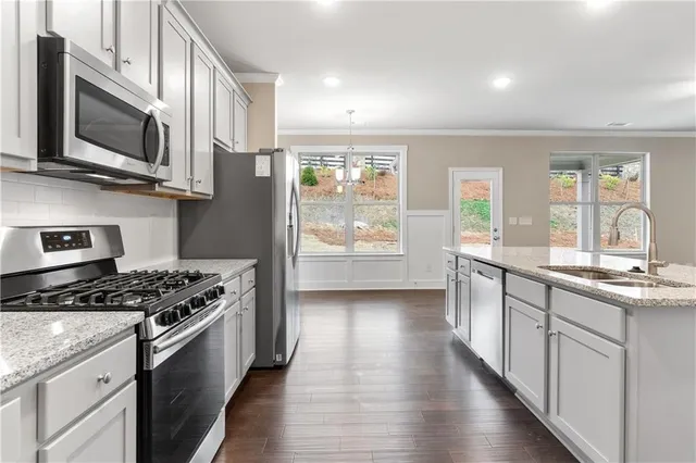 a kitchen with stainless steel appliances granite countertop a stove a sink and a granite counter tops with wooden floors