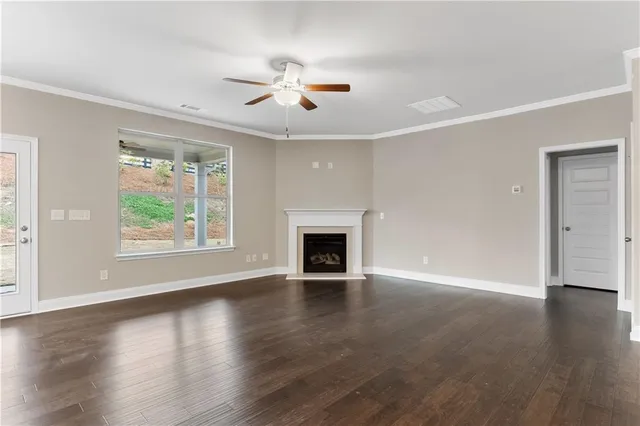 a view of an empty room with wooden floor fireplace and a window