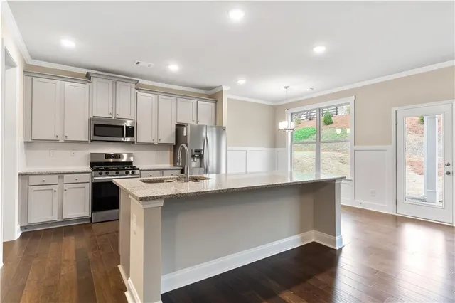 a kitchen with stainless steel appliances a stove top oven a sink a refrigerator and a microwave