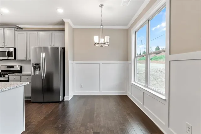 a view of a refrigerator in kitchen and an empty room with wooden floor windows