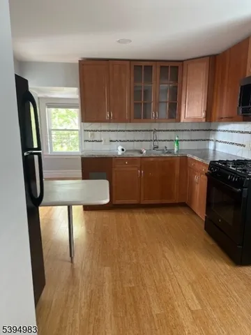 a kitchen with stainless steel appliances granite countertop a refrigerator a sink a stove a microwave oven with wooden floor and cabinets