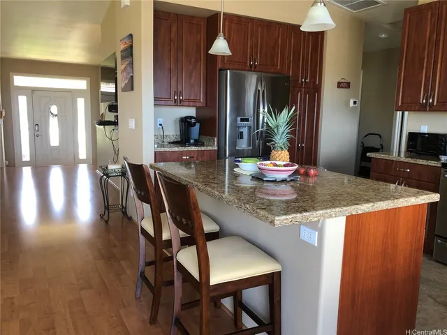 a kitchen with granite countertop kitchen island stainless steel appliances a dining table and chairs