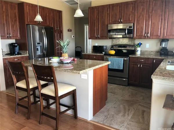 a kitchen with stainless steel appliances kitchen island granite countertop a refrigerator a stove a sink a dining table and chairs