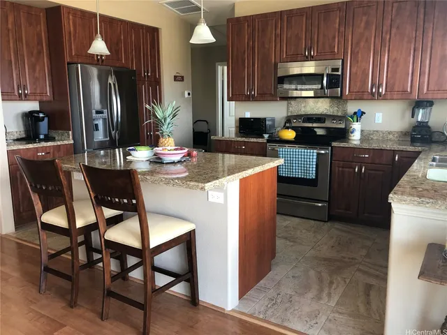 a kitchen with stainless steel appliances kitchen island granite countertop a refrigerator a stove a sink a dining table and chairs