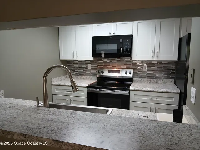 a kitchen with stainless steel appliances kitchen island granite countertop a stove and a microwave with cabinets
