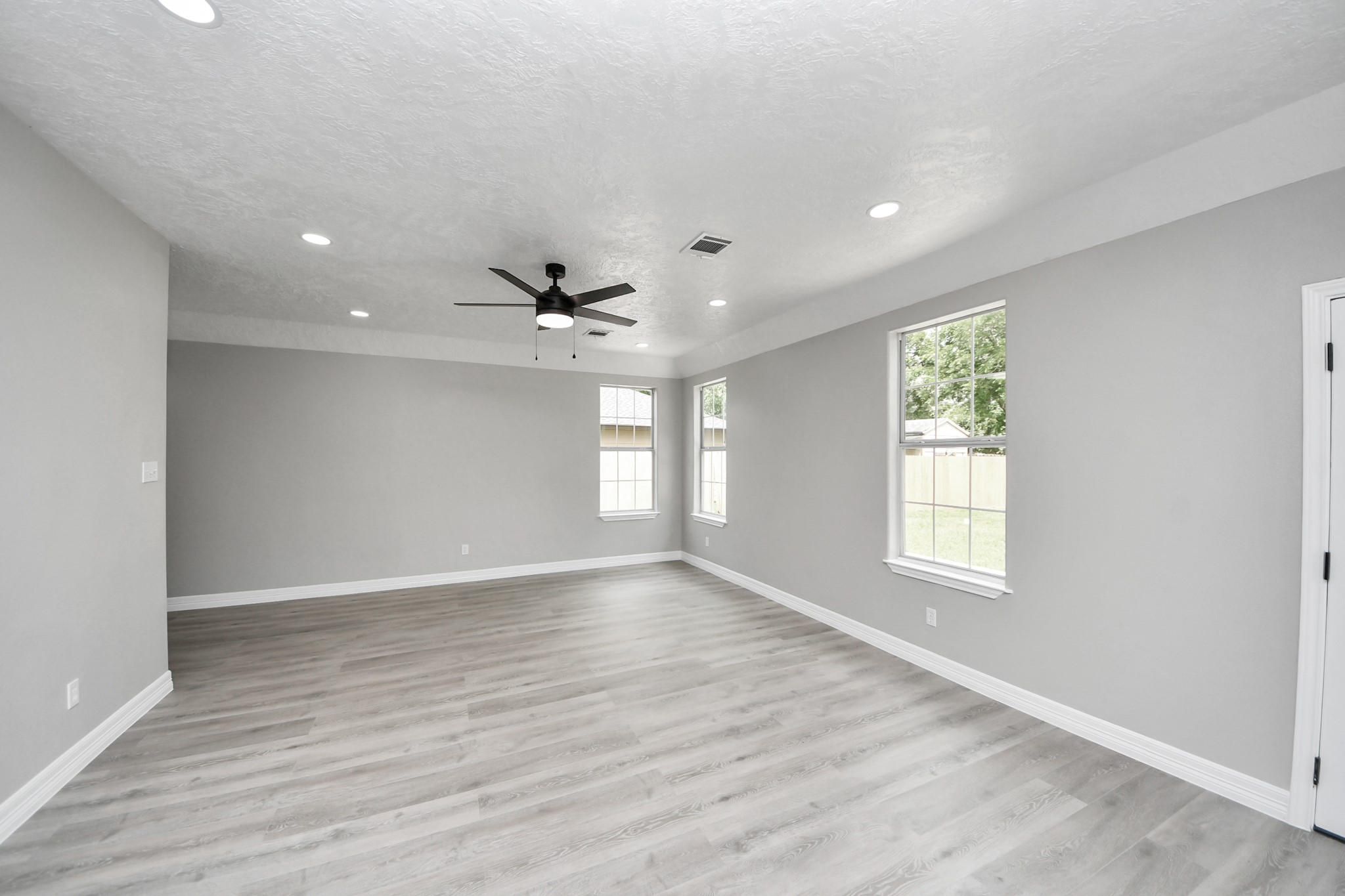 1105 East Kyle Road Clute, TX 77531 - Photo 6 of 44 This spacious, open-concept living area features modern vinyl plank flooring, neutral gray walls, and recessed lighting.