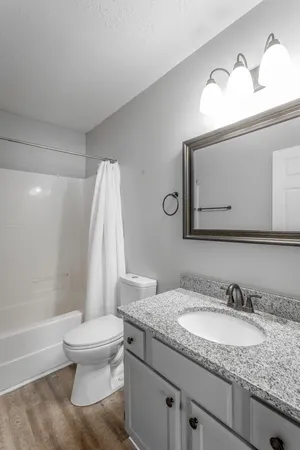 a bathroom with a granite countertop sink vanity mirror and toilet
