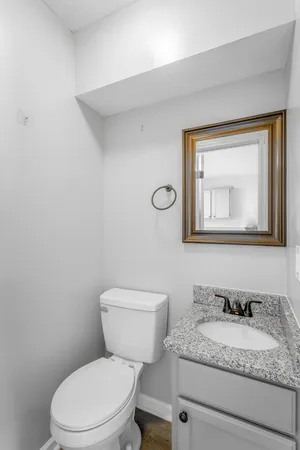 a bathroom with a granite countertop toilet sink and mirror