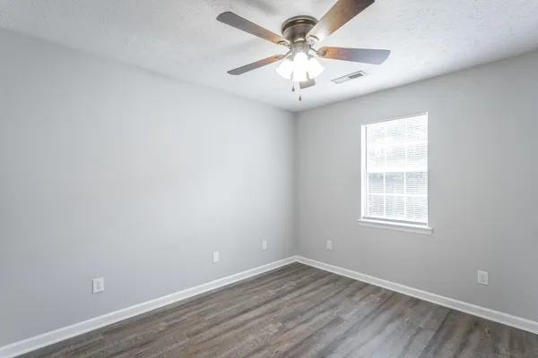 an empty room with a window and a fan