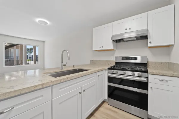 a kitchen with granite countertop white cabinets and stainless steel appliances