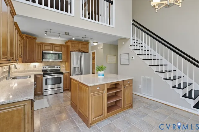 a kitchen with kitchen island granite countertop a sink cabinets and stainless steel appliances